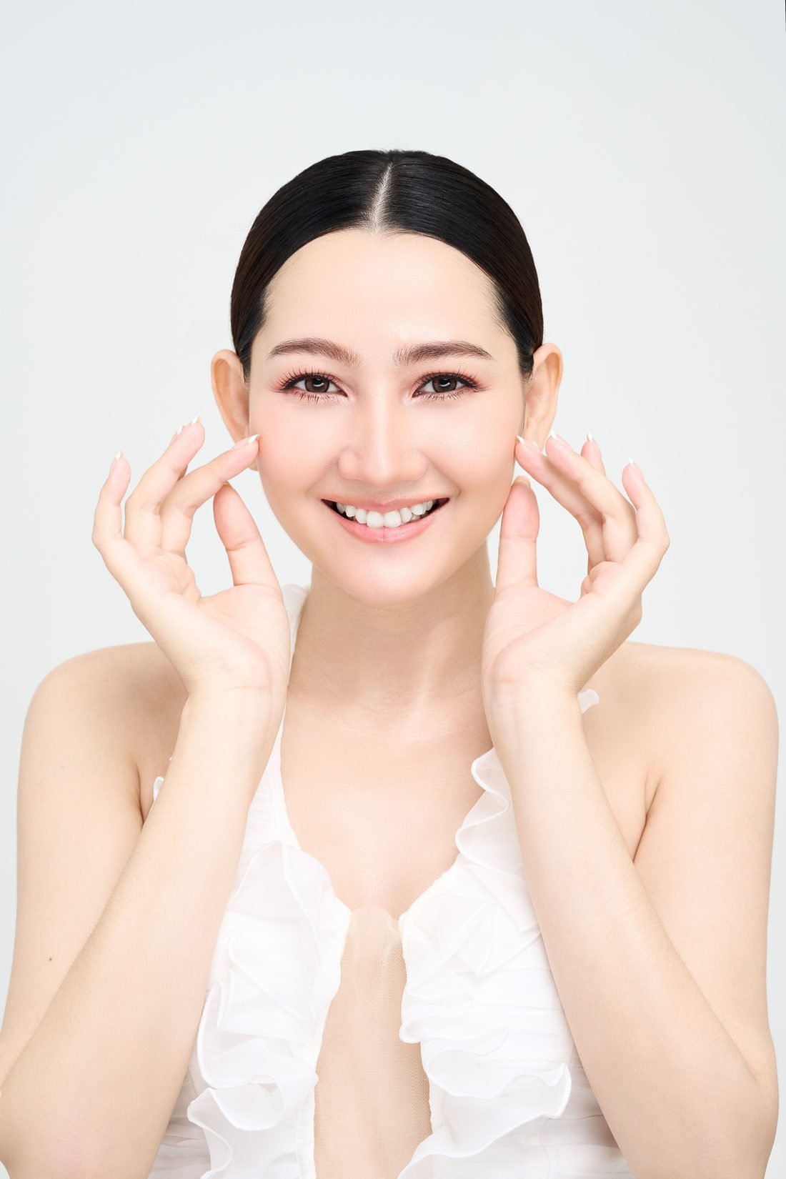 Smiling woman with glowing skin touching her cheeks